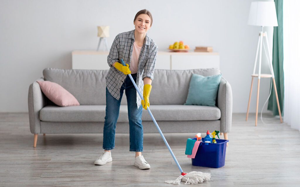 Smiling woman cleaning living room floor, representing professional house clean out services Kent WA for a fresh, organized, and clutter-free home.